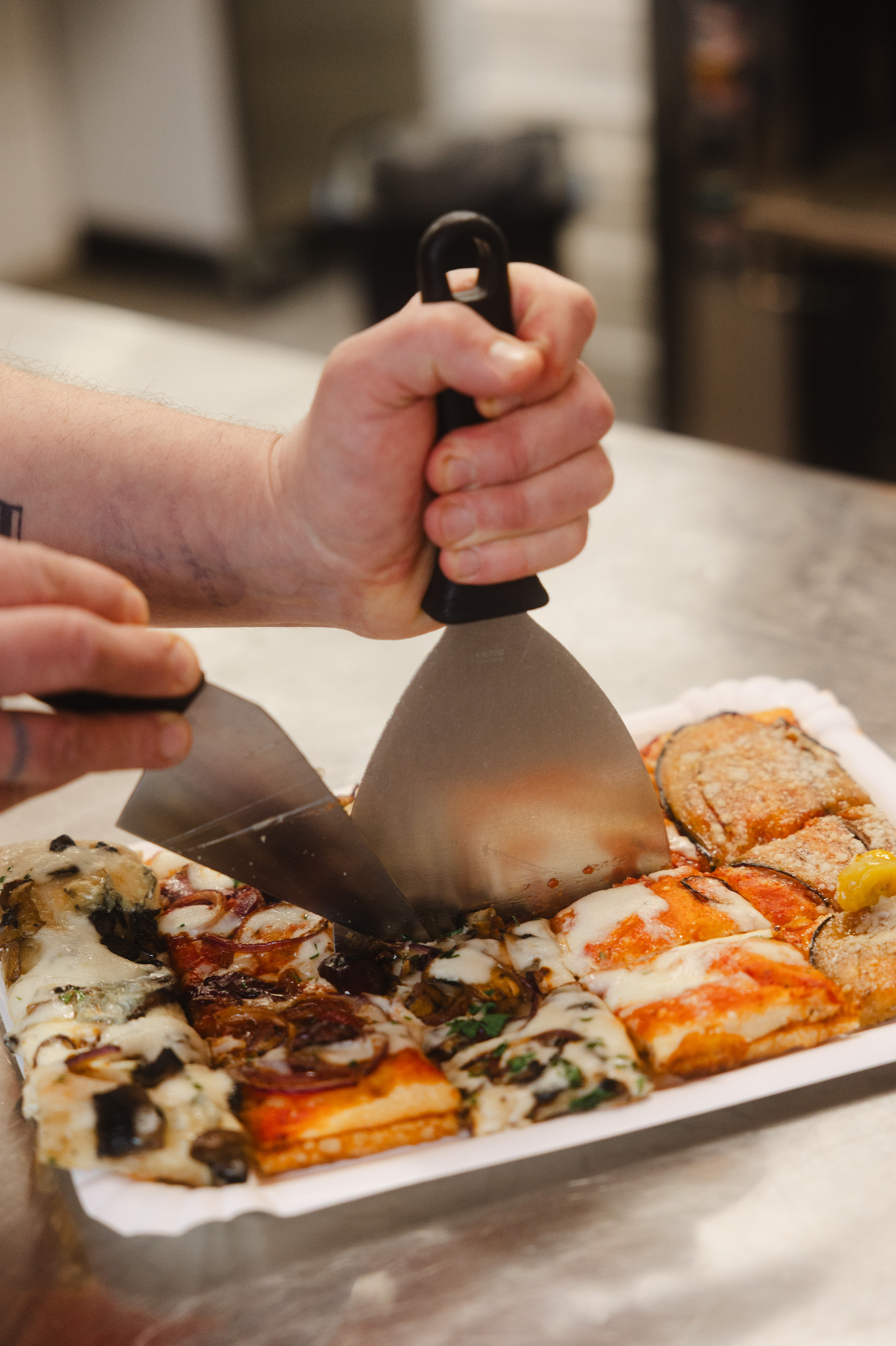 Fresh pizza slices being portioned for a customer