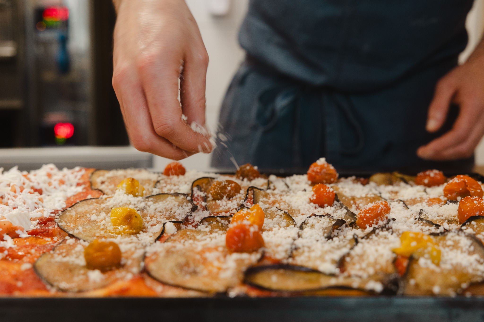 Fresh pizza being finished by hand at Pizzarama